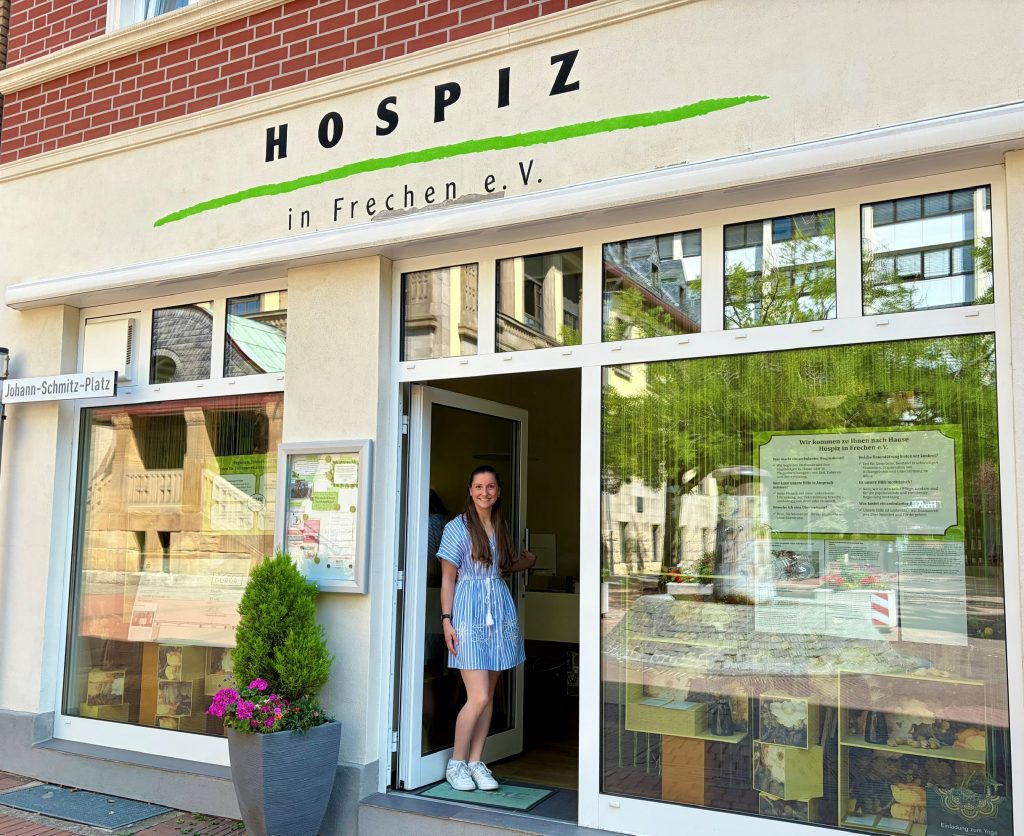 Aufnahme des Schaufensters vom Hospiz in Frechen. Koordinatorin Maike Mannuß steht in der Eingangstür.