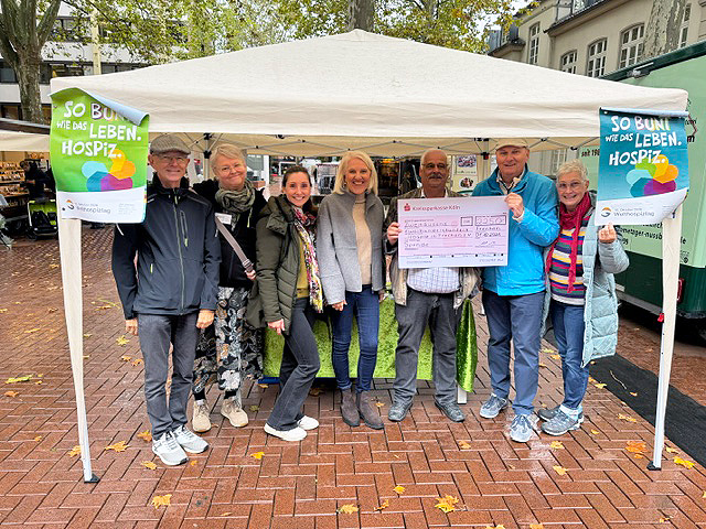 Stand des Hospizes in Frechen e. V. mit Mitarbeitern und Vorstandsmitgliedern des Vereins sowie Vertretern des Aktivkreises Frechen e. V.. Stolz wird der Spendenscheck über 2.250 Euro präsentiert.